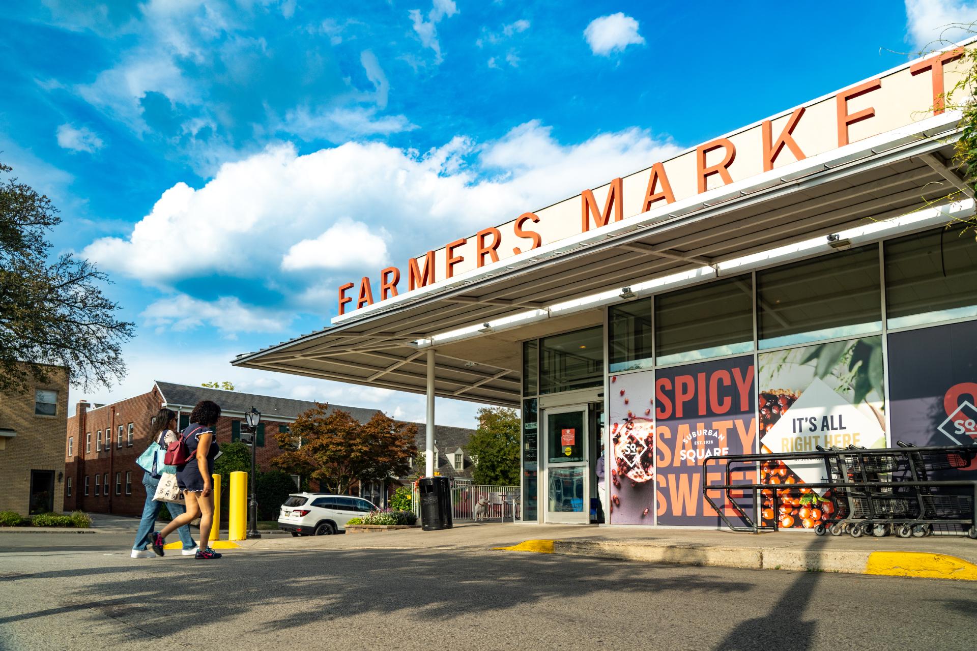 Two women walking into the well-stocked farmers market at Suburban Square